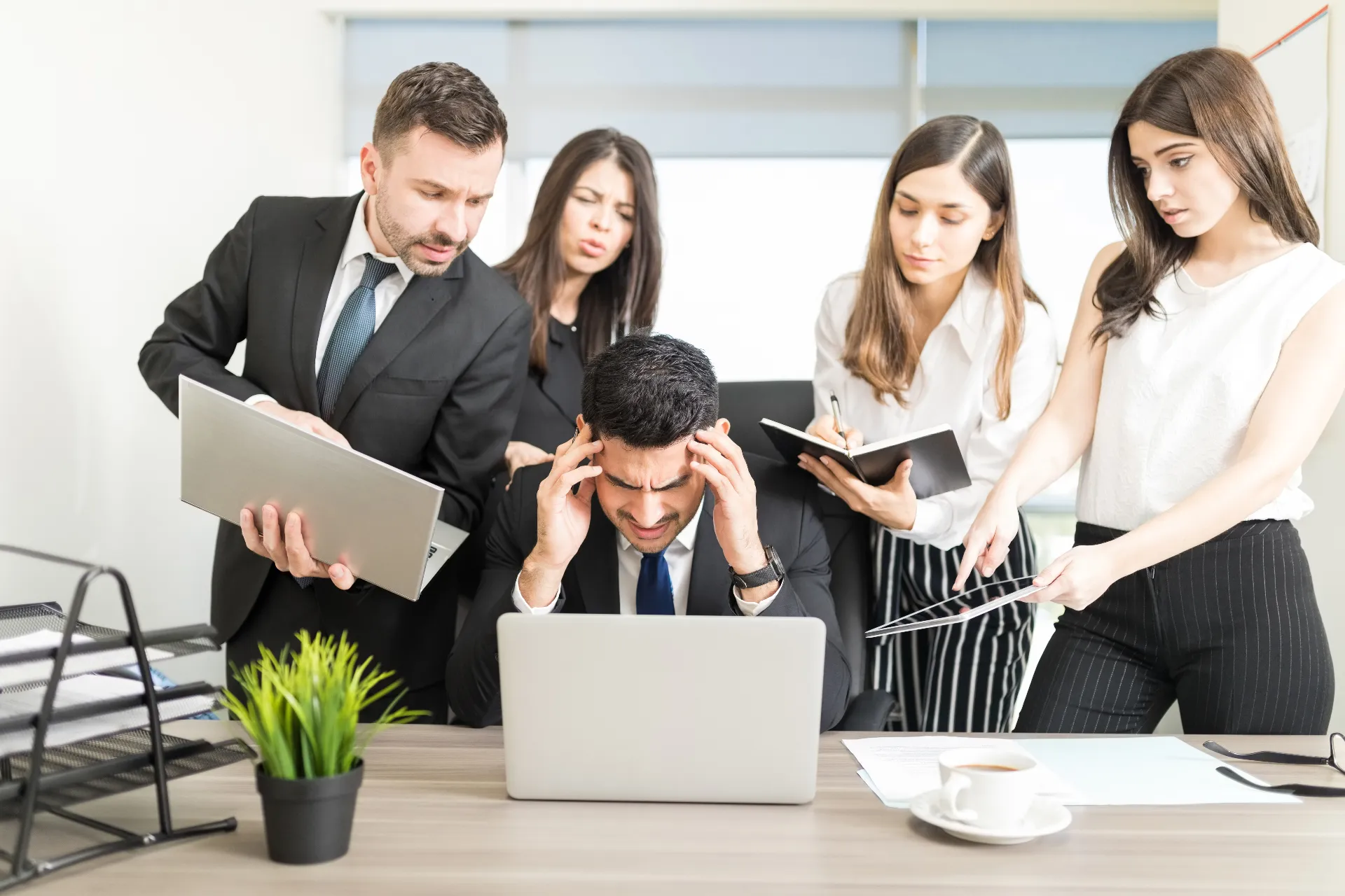 Stressed businessman with team members overwhelming him with tasks and documents